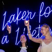 Grads raise their glasses in front of Laker for a Lifetime sign